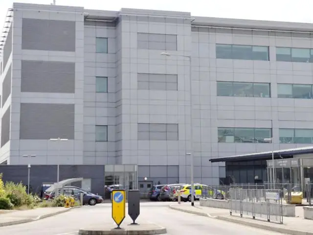 Picture of grey office building with parked cars at the front
